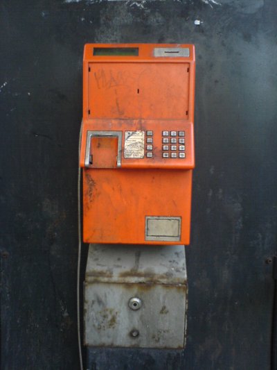 distressed orange pay phone in kiosk 